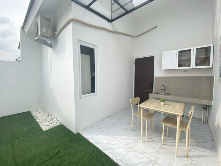 Area belakang rumah Ganda Arum Residence 7 Bekasi dengan dapur outdoor dan taman rumput hijau.