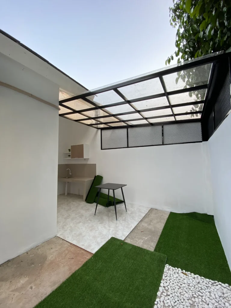 Area belakang rumah di Pesona Arum Residence Bekasi dengan dapur semi outdoor, kanopi transparan, dan lantai yang rapi untuk aktivitas rumah tangga.