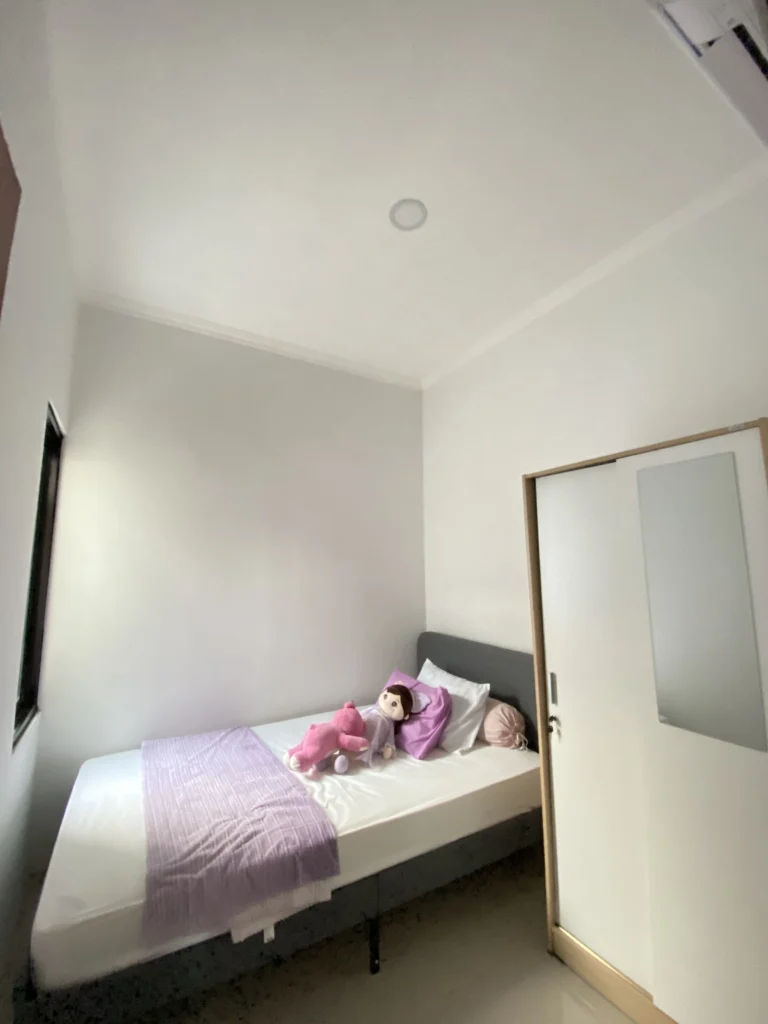 Kamar tidur anak di Pesona Arum Residence Bekasi dengan kasur single, AC, dekorasi anak, dan pencahayaan alami dari jendela.