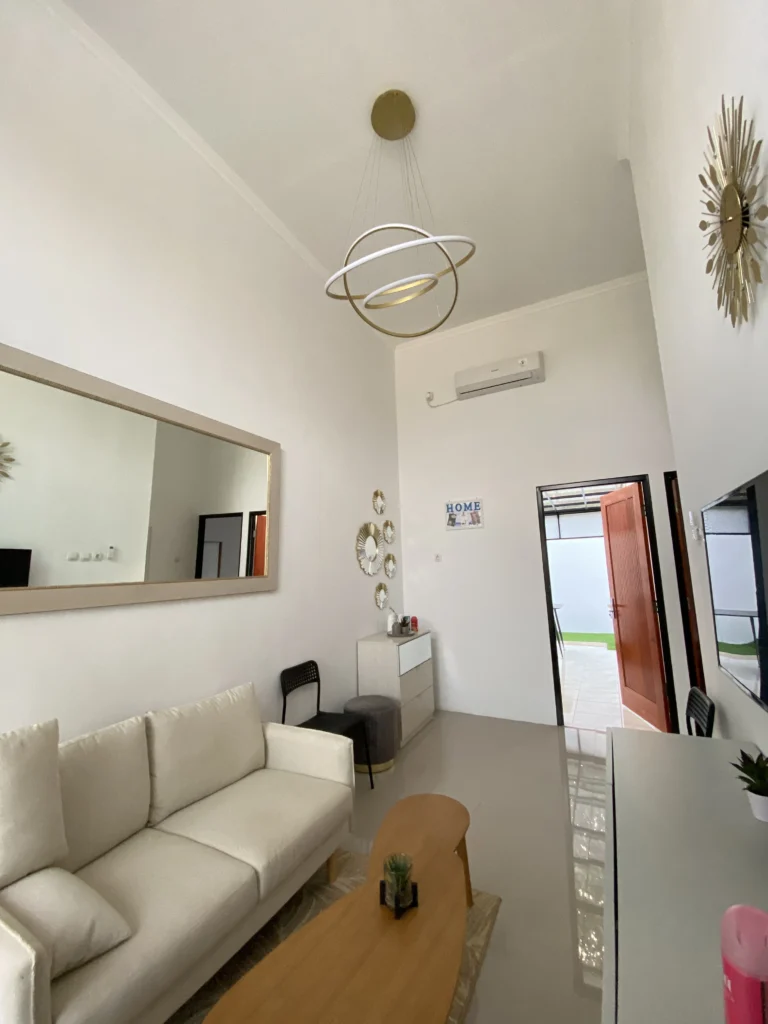 Ruang keluarga modern minimalis di Pesona Arum Residence Bekasi dengan sofa putih, meja kayu, AC, dan dekorasi interior elegan.